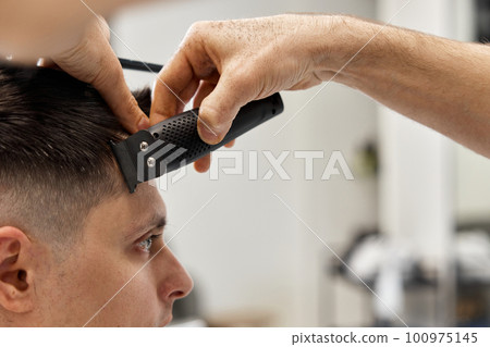Barber shaving caucasian man in barber shop. 100975145