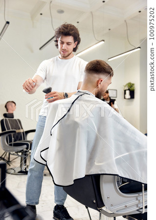 Barber trim hair with clipper on handsome bearded man 100975202