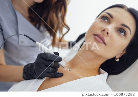 Beautiful caucasian young woman is doing a mole removal procedure in a modern beauty cosmetic dermatological clinic 100975298
