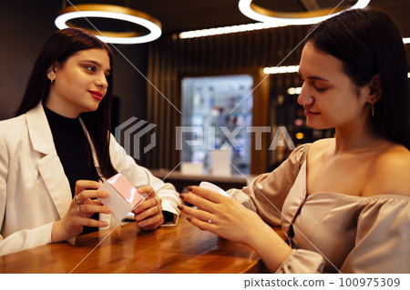 Female receptionist working in beauty salon and offers cosmetics to female customer 100975309