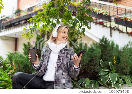 young girl freelancer listens to music in headphones and walks along the city street young girl freelancer listens to music in headphones and walks along the city street 100975498