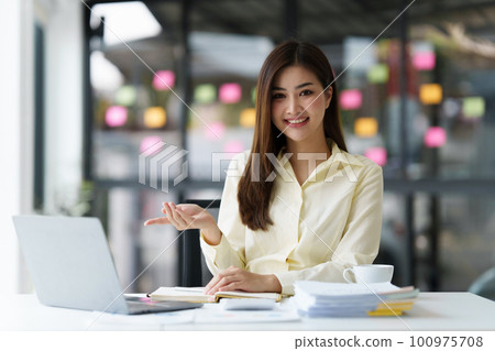 Beautiful Asian Banker or Accountant makes financial report and tax, analyzes profits. Accountant checks status of financial 100975708