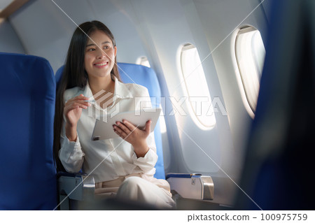 Beautiful Asian businesswoman working with digital tablet in aeroplane. working, travel, business concept Beautiful Asian businesswoman working with digital tablet in aeroplane. working, travel, business concept 100975759