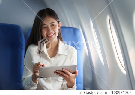 Beautiful Asian businesswoman working with digital tablet in aeroplane. working, travel, business concept 100975762