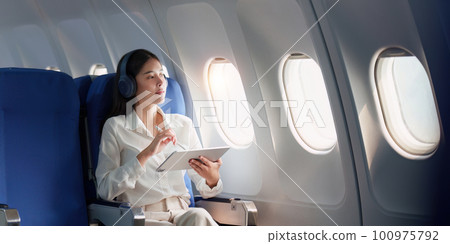 Beautiful Asian businesswoman working with digital tablet in aeroplane. working, travel, business concept Beautiful Asian businesswoman working with digital tablet in aeroplane. working, travel, business concept 100975792