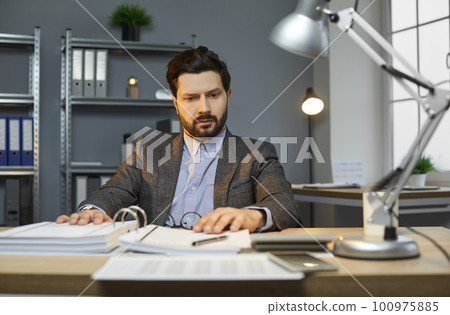 Young attractive business man with beard and mustache in suit working at the desk on his workplace 100975885