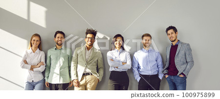 Successful smiling team of employees standing near gray wall 100975899