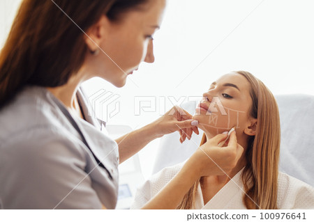 Doctor checking woman face skin in cosmetology clinic before plastic surgery 100976641