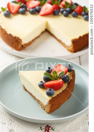 Piece of Classic New York Cheesecake with fresh berries closeup on the plate. Vertical 100976832
