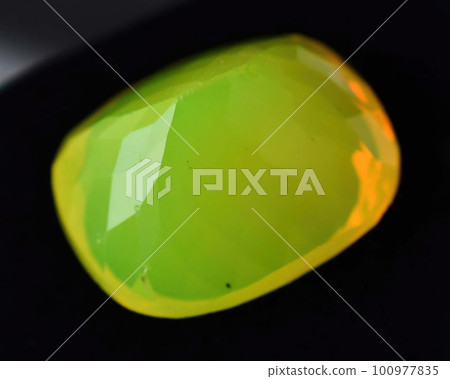 Natural gemstone yellow neon opal on black background 100977835