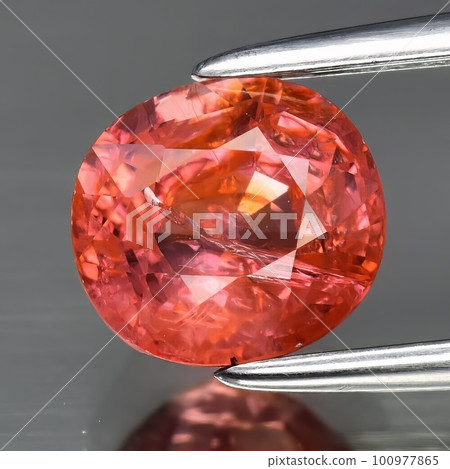 Natural gemstone orange hessonite garnet on gray background 100977865