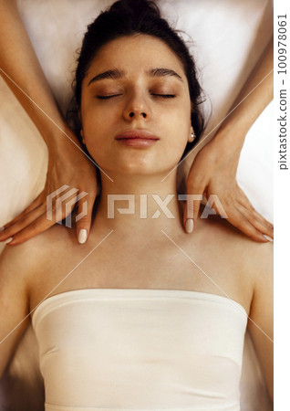 Close up portrait of a young beautiful woman getting facial massage 100978061
