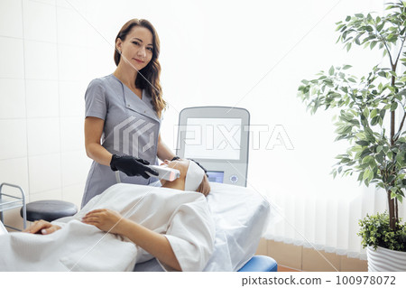 Portrait of relaxed young female client getting SMAS ultrasound face lifting massage 100978072