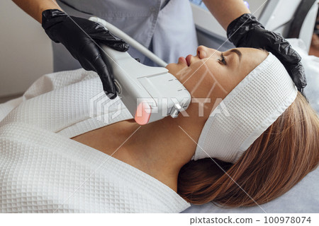Portrait of relaxed young female client getting SMAS ultrasound face lifting massage 100978074