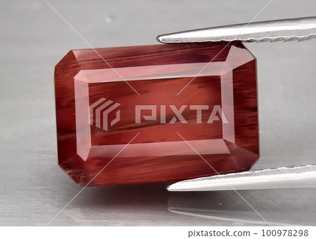 Natural gemstone orange andesine on gray background 100978298