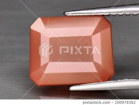 Natural gemstone orange andesine on gray background 100978362