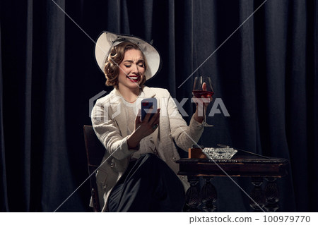 Adorable woman wearing costume talking at phone with bright emotional facial expression over dark background. Old-style photo 100979770