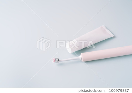Pink electric toothbrush with toothpaste on a blue background 100979887