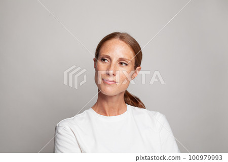 Mature female model mid adult woman with clear skin looking away at copy space on grey background Mature female model mid adult woman with clear skin looking away at copy space on grey background 100979993