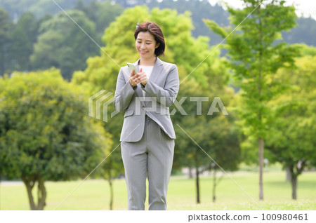 A woman in a business suit holding a smartphone A woman in a business suit holding a smartphone 100980461
