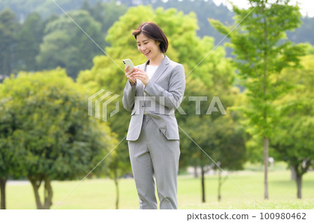 A woman in a business suit holding a smartphone 100980462