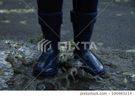 Person in rubber boots outdoor in rainy weather Person in rubber boots outdoor in rainy weather 100983214