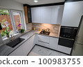 A spacious and updated kitchen with a white color scheme and marble floor 100983755