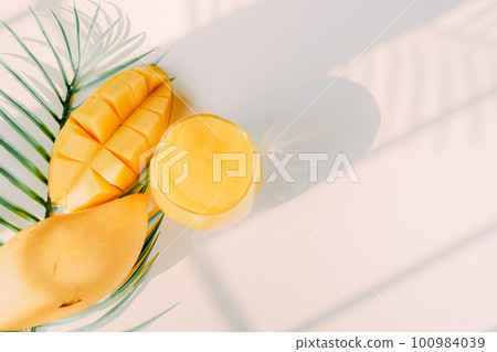 top view and flat lay summer fruit from mango slice and juice with shadow of tropical leaf and white background 100984039
