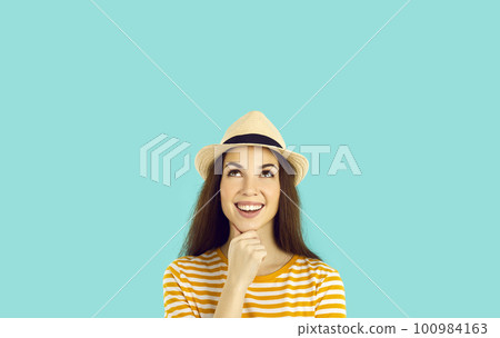 Smiling joyful young woman pondering cool idea or imagining something on light blue background. Smiling joyful young woman pondering cool idea or imagining something on light blue background. 100984163
