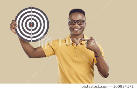 Smiling biracial man point at darts board Smiling biracial man point at darts board 100984171