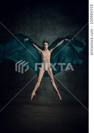 Portrait of beautiful dancer flying with silk fabric over dark green background 100984359