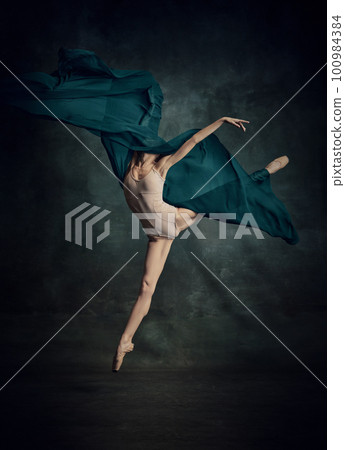 Weightless easy jump. Sensual ballerina with stretched feet dancing with fabric isolated over dark green background 100984384