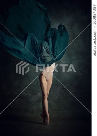 Young girl dancing with elegance movements and fabric cover the face over dark green background 100984387