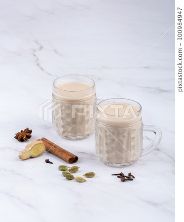 Glass cups with masala tea and cinnamon, anise with cloves and ginger root with cardamom. Glass cups with masala tea and cinnamon, anise with cloves and ginger root with cardamom. 100984947