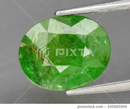 Natural grossular garnet gemstone on gray background Natural grossular garnet gemstone on gray background 100985004