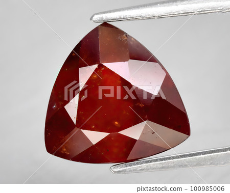 Natural gemstone orange hessonite garnet on gray background Natural gemstone orange hessonite garnet on gray background 100985006