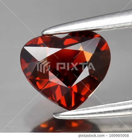 Natural gemstone red spessartine garnet on a gray background 100985008