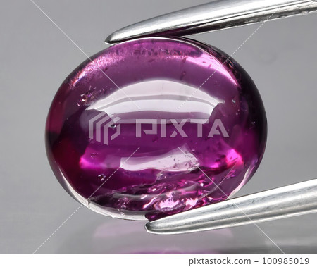 Natural gemstone red rhodolite garnet on gray background 100985019
