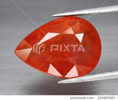 Natural gemstone orange Padparadscha sapphire on gray background 100985063