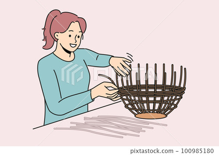 Smiling woman weaving basket from wicker  100985180