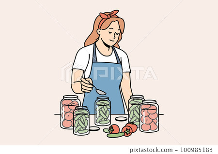 Woman in apron canning vegetables in bottles 100985183
