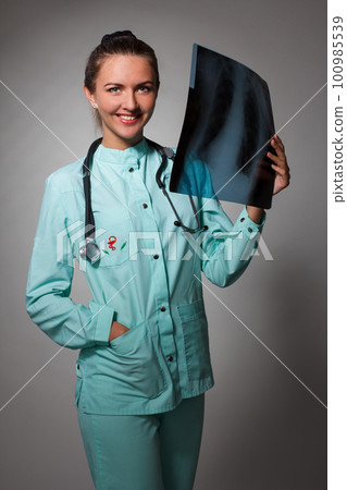 Young beautiful brunette doctor woman wearing stethoscope holding chest xray with a happy face standing and smiling with a confident smile showing teeth 100985539