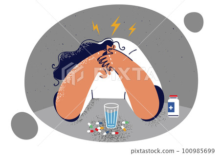 Woman sitting at table with pills suffering from headache or migraine due to overwork  100985699