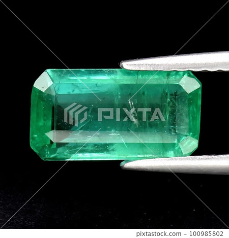 Natural gemstone green emerald on gray background 100985802