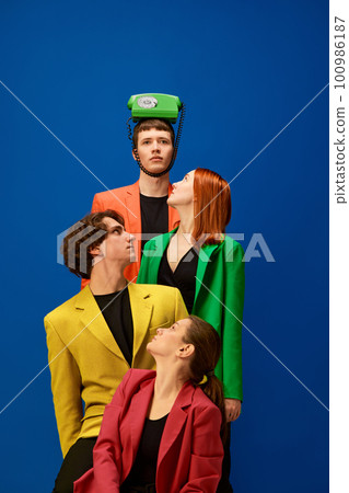 Men and women wearing colorful jackets looking at phone over blue background Men and women wearing colorful jackets looking at phone over blue background 100986187