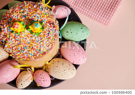 Cropped view of Easter cake with selective focus on colorful eggs on red napkin over pink background. Celebration of Orthodox and Catholic Easter in spring. Christianity. Religious Christian holiday 100986400