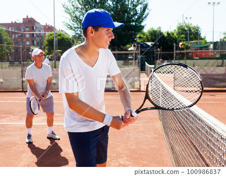 grandfather and grandson playing tennis court 100986837
