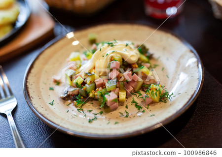 Delicious potato salad with slices of ham and mushrooms close up 100986846