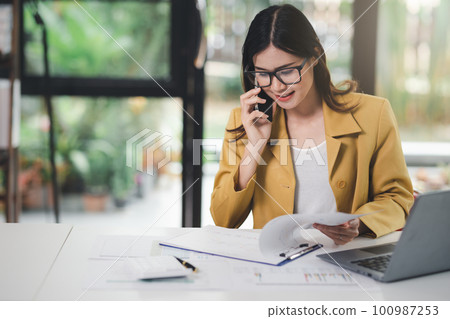 Concept of business office woman working,Businesswoman using smartphone talking to her client about invesment plan and checking  analyzing document and business investment graph data in workstation. Concept of business office woman working,Businesswoman using smartphone talking to her client about invesment plan and checking  analyzing document and business investment graph data in workstation. 100987253
