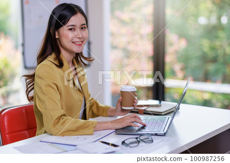 Concept of business office woman working,Businesswoman smile while working about her invesment plan with analyzing document and business investment graph data by using laptop on desk in workstation. Concept of business office woman working,Businesswoman smile while working about her invesment plan with analyzing document and business investment graph data by using laptop on desk in workstation. 100987256